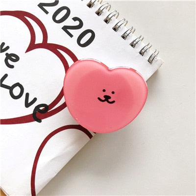 Cartoon Derp Heart Phone Socket. Attach these to your phone so you can hold it securely, prop it up whilst watching shows, or just fiddle around with it. Compatible with any phone!